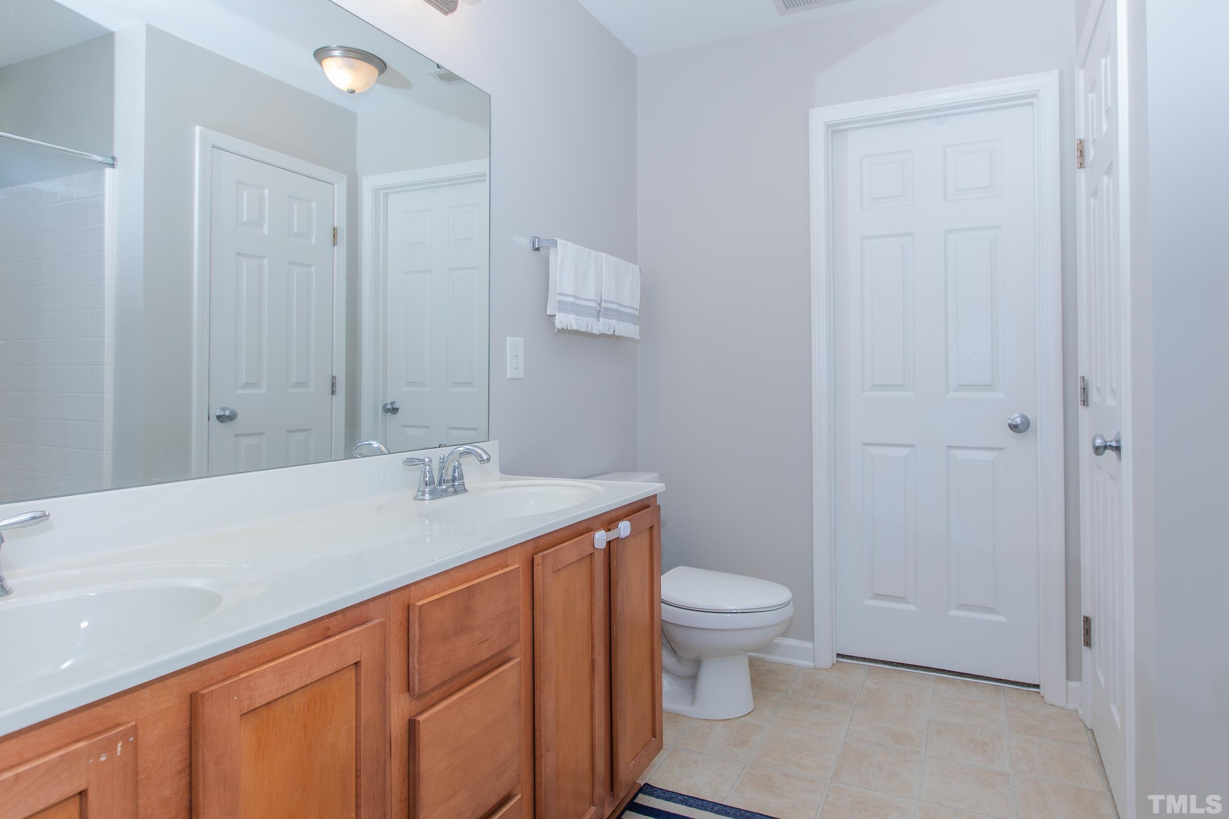 4228 Amber Stone Way Durham, NC 27704 - Photo 29 of 34 a bathroom with a granite countertop sink a toilet and a shower