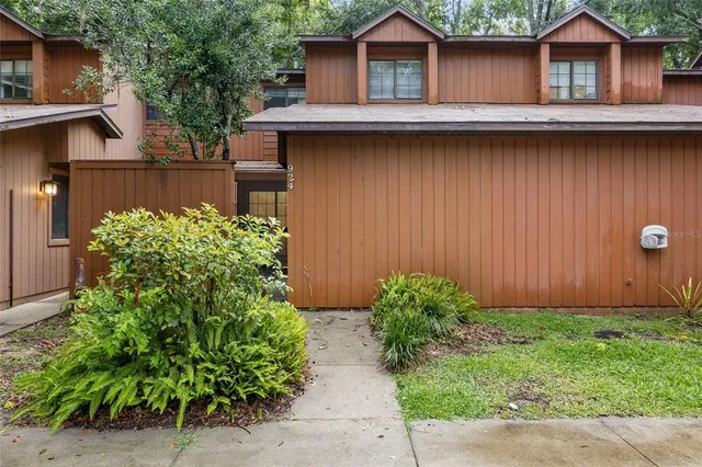 a view of a wooden house with a yard and plants
