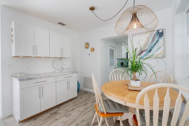 a kitchen with stainless steel appliances granite countertop a white cabinets a sink a dining table and chairs