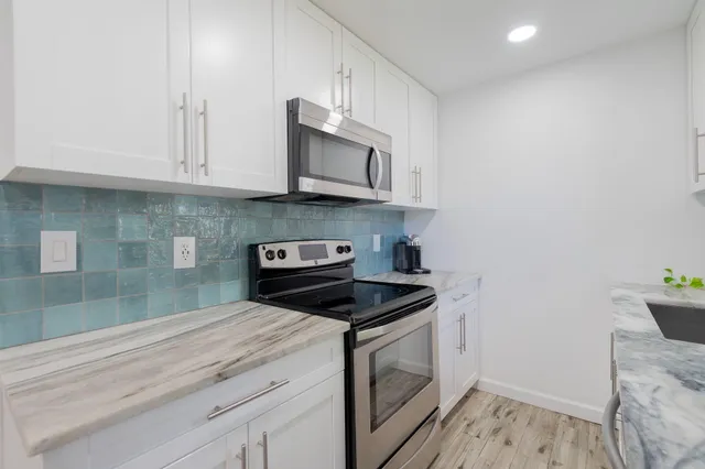 a kitchen with stainless steel appliances granite countertop a stove a sink and a microwave