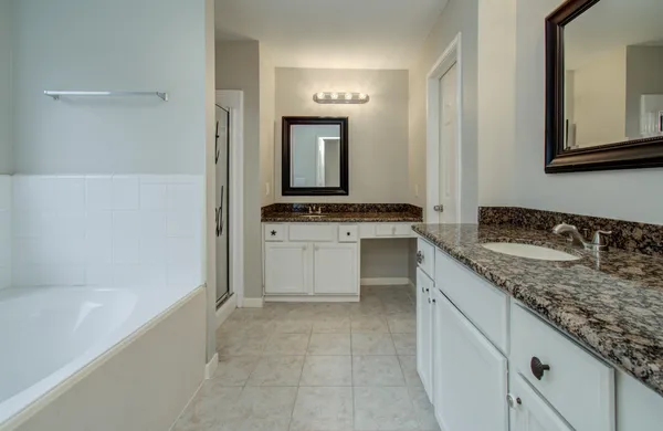 a bathroom with a granite countertop sink a mirror and a bathtub