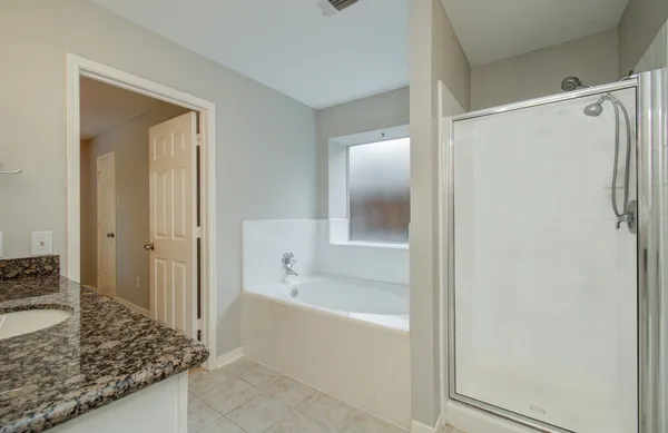 a bathroom with a granite countertop bathtub shower and vanity