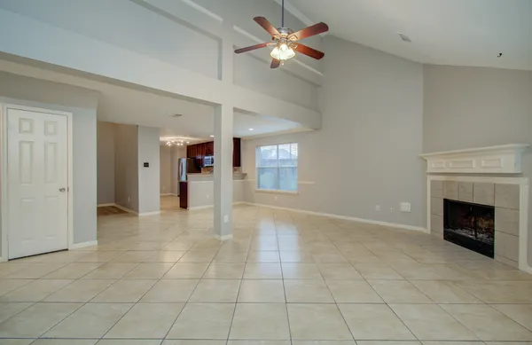 a view of a livingroom with a fireplace a chandelier fan and windows