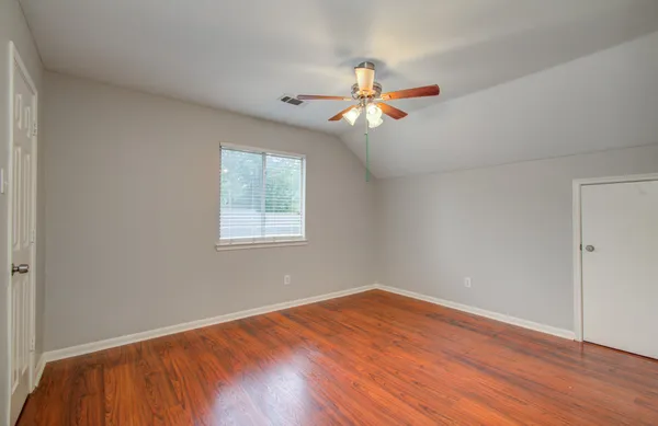 a view of a room with wooden floor and a ceiling fan