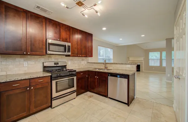 a kitchen with stainless steel appliances granite countertop wooden cabinets a stove top oven a sink and dishwasher