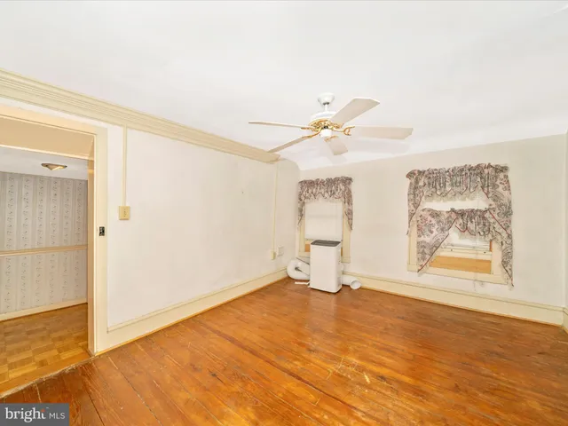 a view of empty room with wooden floor and fan