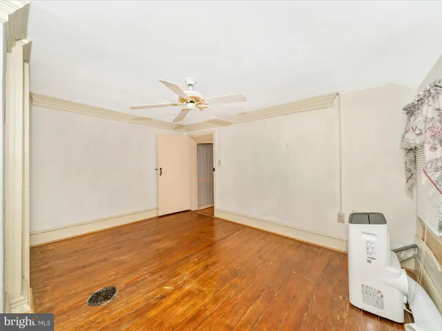 an empty room with wooden floor fan and windows