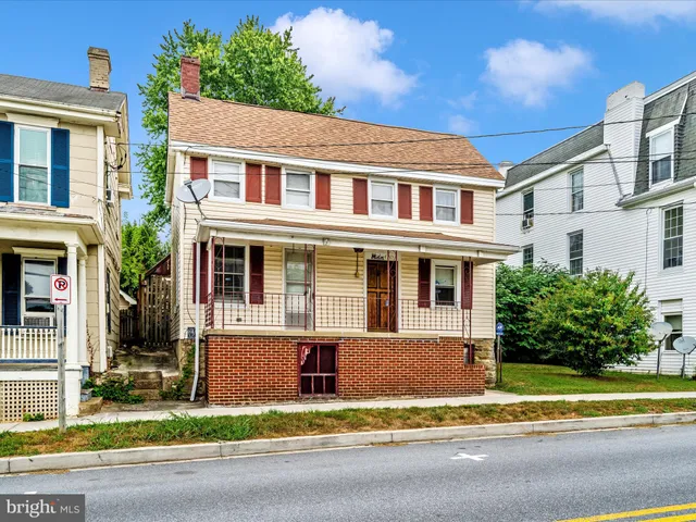 a front view of a house with a garden and trees
