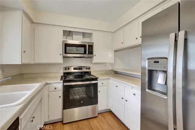 a kitchen with cabinets stainless steel appliances and wooden floor