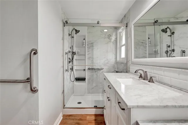 a bathroom with a tub sink vanity granite and shower