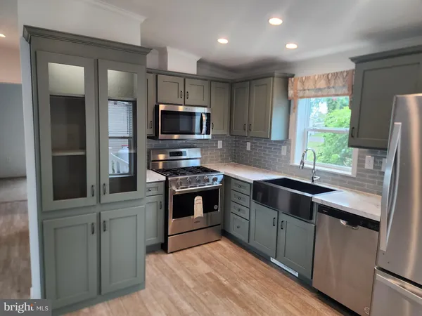a kitchen with kitchen island granite countertop stainless steel appliances cabinets a sink and a window