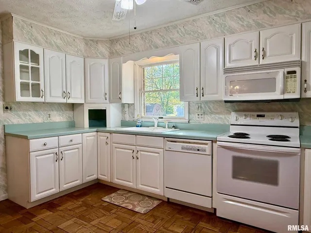 a kitchen with granite countertop white cabinets stainless steel appliances and a window