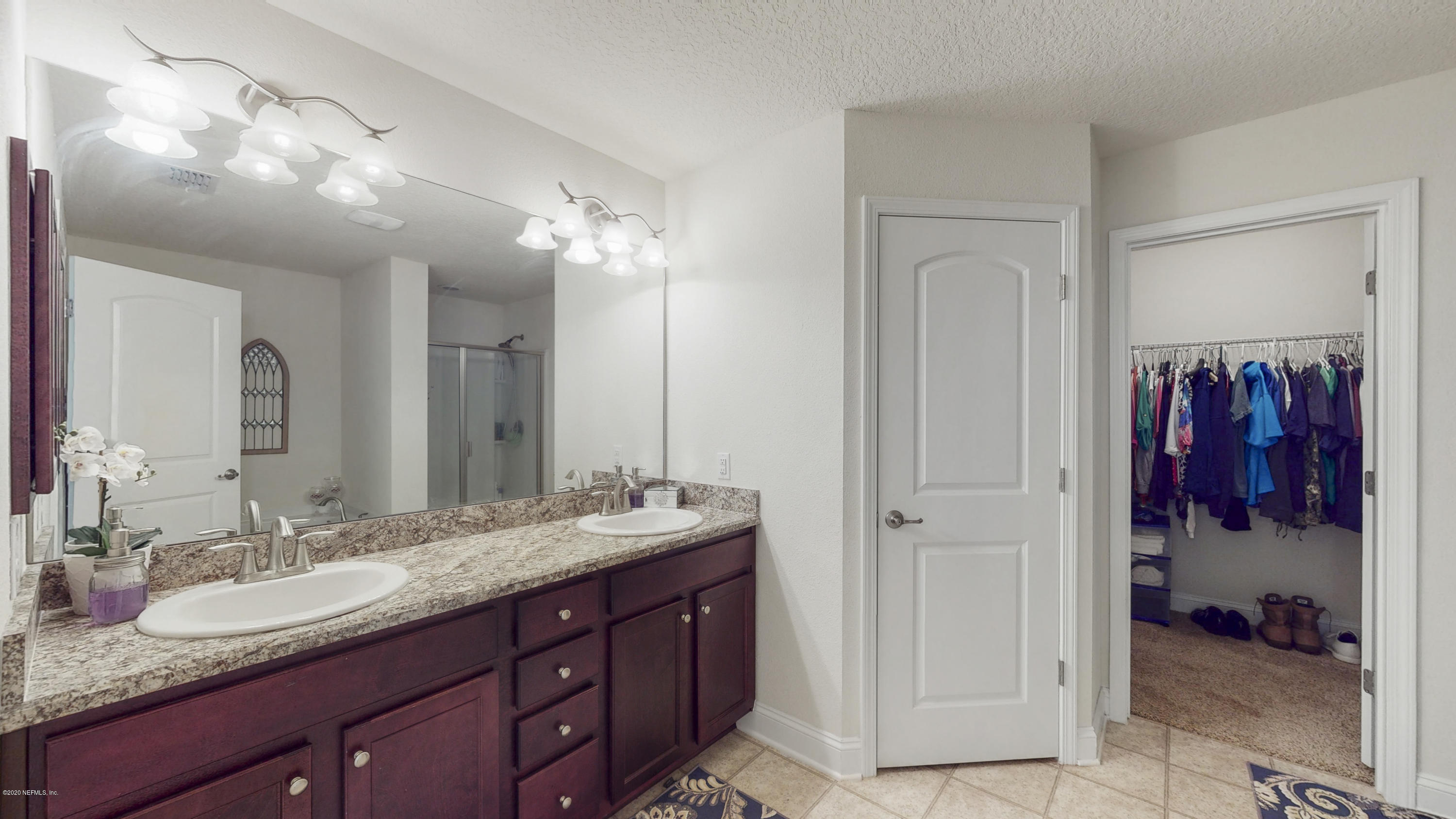 88101 Maybourne Road Yulee, FL 32097 - Photo 14 of 22 a bathroom with a granite countertop sink a mirror and a shower