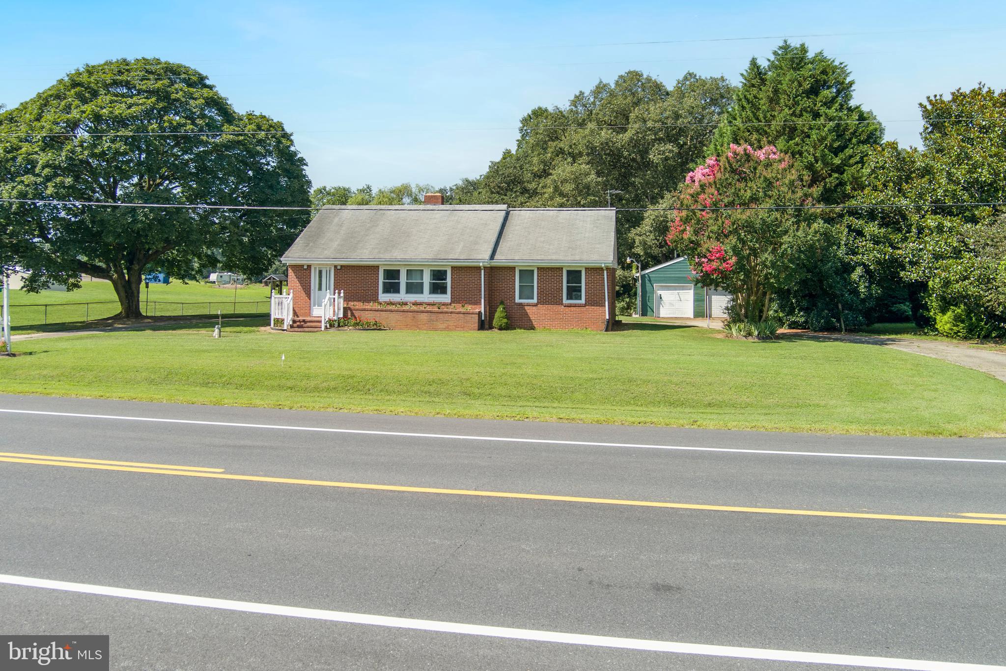 a view of a big house with a big yard and large trees
