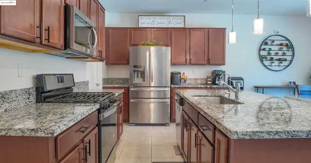 a kitchen with stainless steel appliances granite countertop a sink dishwasher stove and refrigerator with wooden cabinets
