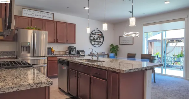 a kitchen with kitchen island granite countertop a sink a counter space appliances and cabinets