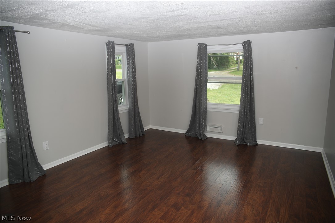1087 Krumroy Road Akron, OH 44306 - Photo 5 of 23 Spacious room featuring rich wood-finish flooring, light gray walls, white baseboards, and multiple windows