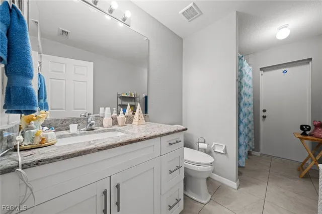 a bathroom with a granite countertop sink a toilet and a mirror