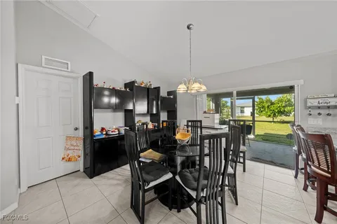 a view of a dining room and livingroom furniture a rug a chandelier and kitchen view