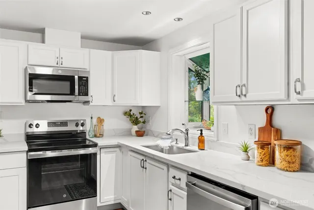 a kitchen with stainless steel appliances a stove a sink a microwave and cabinets
