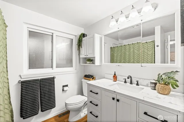 a bathroom with a granite countertop sink toilet and a mirror