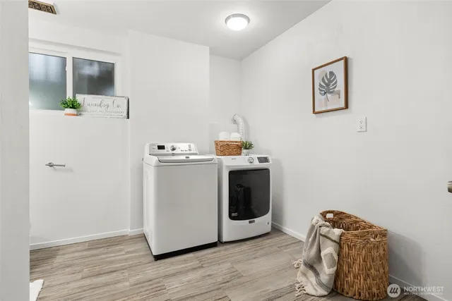 a utility room with fridge and wooden floor