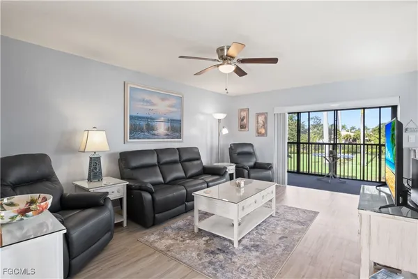a living room with furniture floor to ceiling window and a flat screen tv