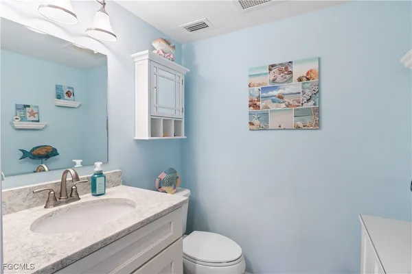 a bathroom with a granite countertop sink mirror vanity and toilet