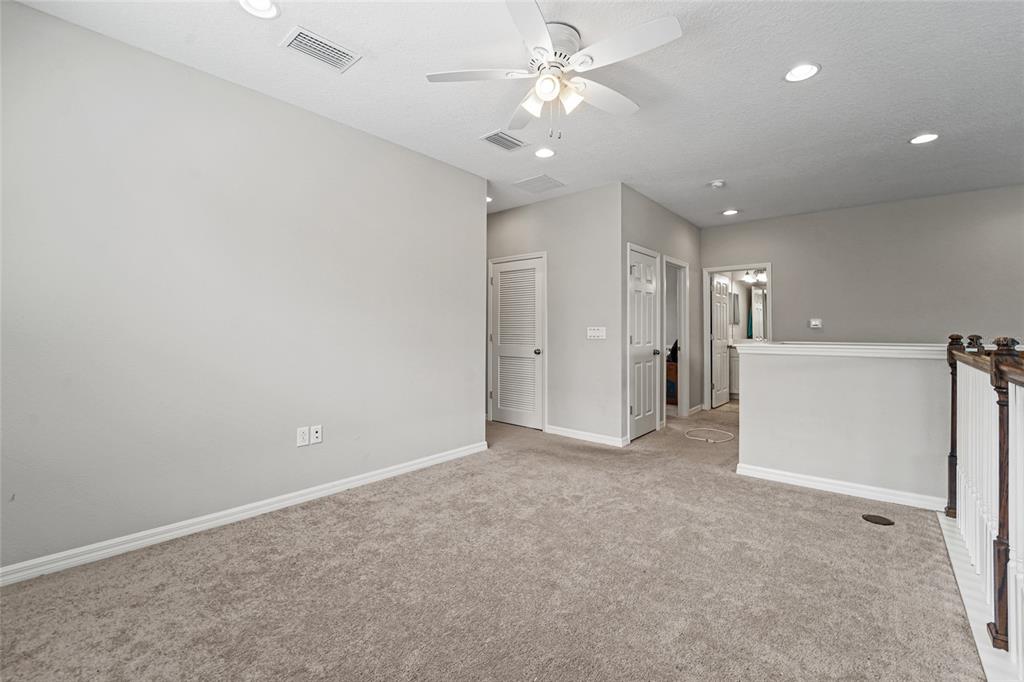 8903 Arabella Lane Seminole, FL 33777 - Photo 38 of 47 an empty room with a ceiling fan and a view of a kitchen