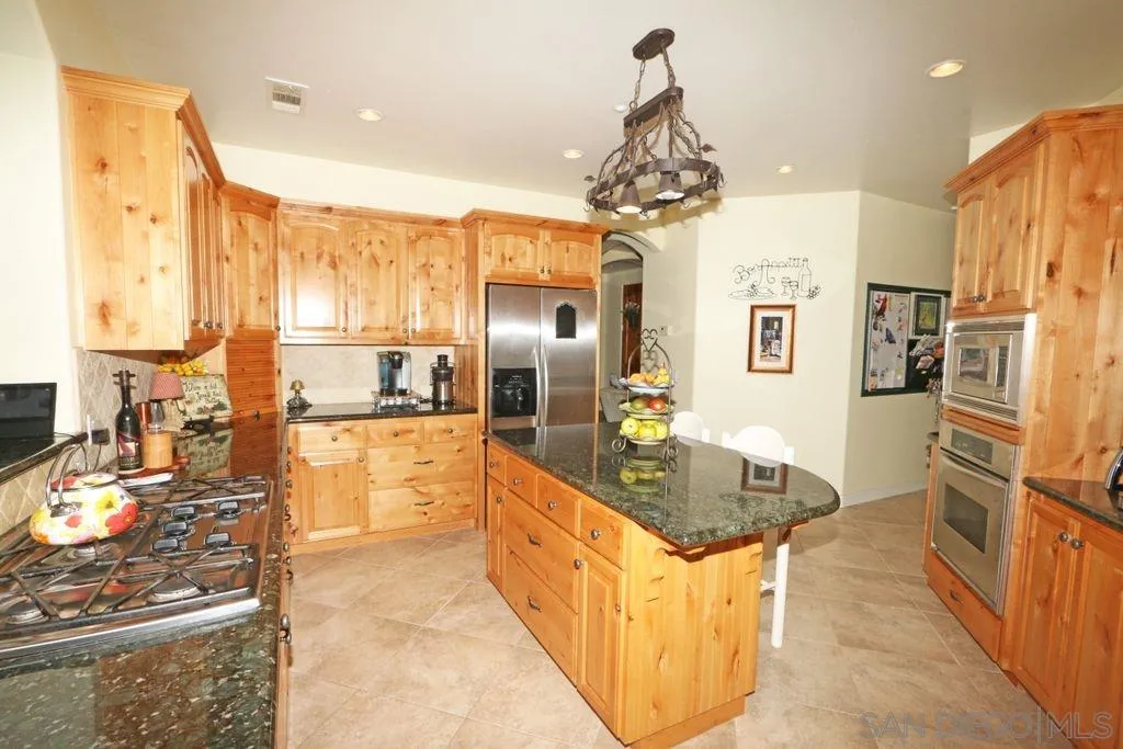 24568 Rutherford Road Ramona, CA 92065 - Photo 21 of 25 a large kitchen with kitchen island granite countertop a large counter top stainless steel appliances and cabinets