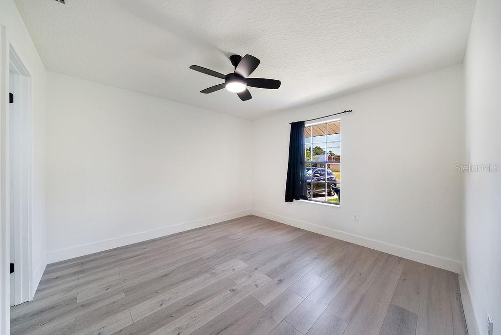 682 Degroodt Road Southwest Palm Bay, FL 32908 - Photo 15 of 27 an empty room with wooden floor ceiling fan and windows