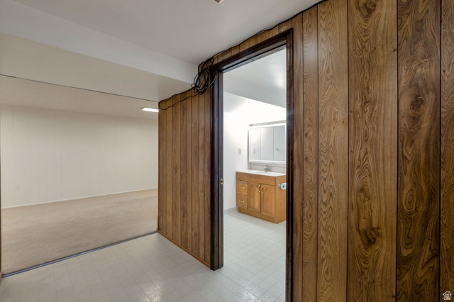 447 550 South Bountiful, UT 84010 - Photo 14 of 25 Wood-panel wall opening to a room featuring a vanity with a white countertop and a mirrored medicine cabinet