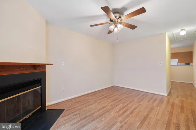 an empty room with wooden floor and a ceiling fan
