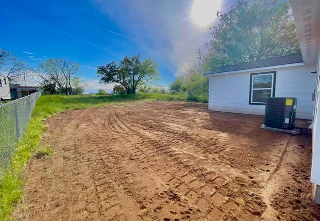 a view of a backyard with plants and large trees