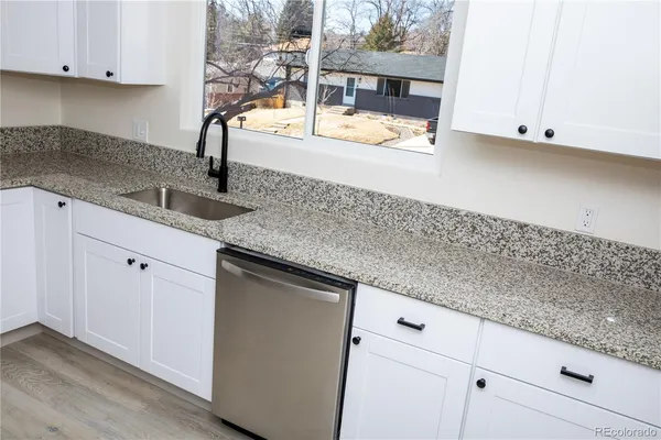 a kitchen with granite countertop white cabinets and a sink