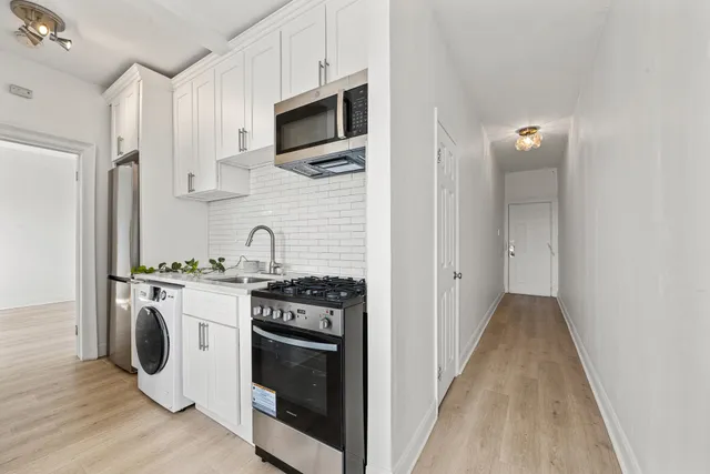 a kitchen with stainless steel appliances a stove a microwave and white cabinets