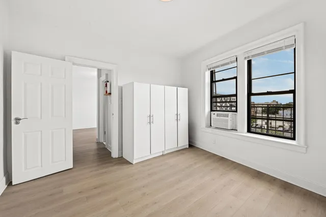 a view of an empty room with a window and wooden floor