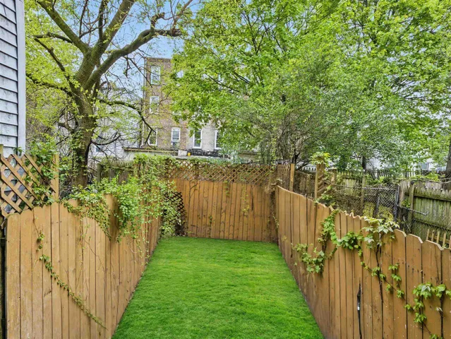a view of a pathway of a yard with wooden fence and plants