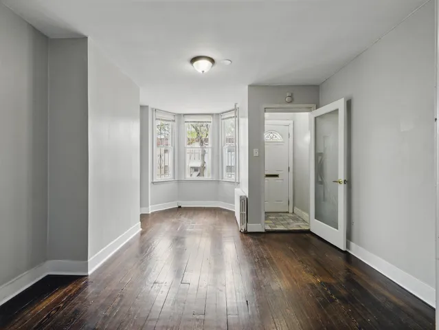 an empty room with wooden floor and mirror