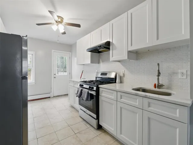 a kitchen with stainless steel appliances granite countertop a sink a stove a refrigerator and cabinets