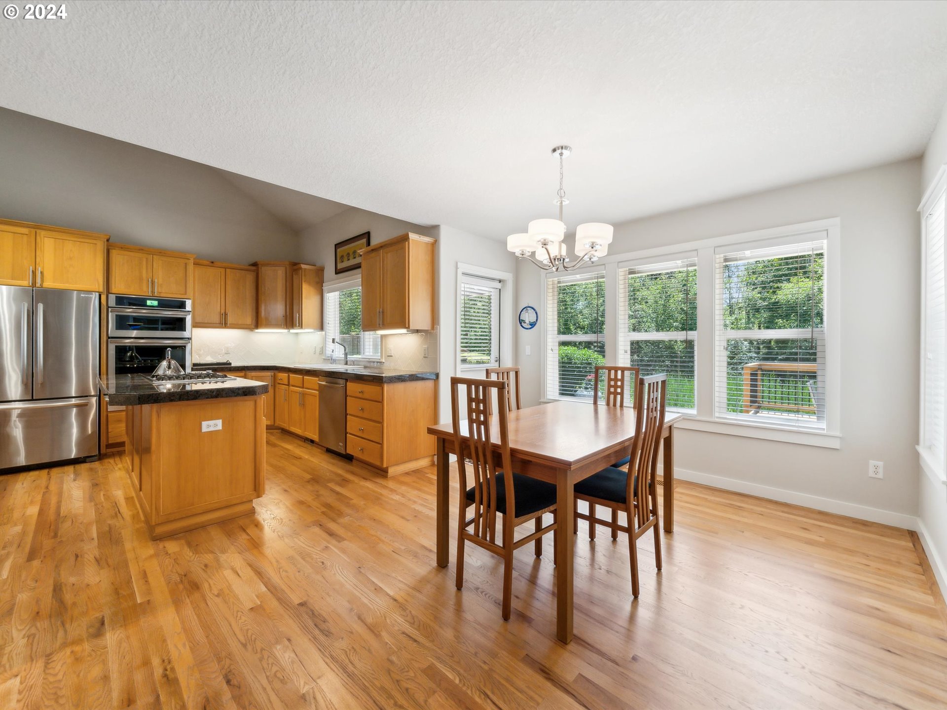 16368 Northwest Graf Street Portland, OR 97229 - Photo 23 of 46 a kitchen with stainless steel appliances granite countertop a stove top oven a sink dishwasher a dining table and chairs with wooden floor