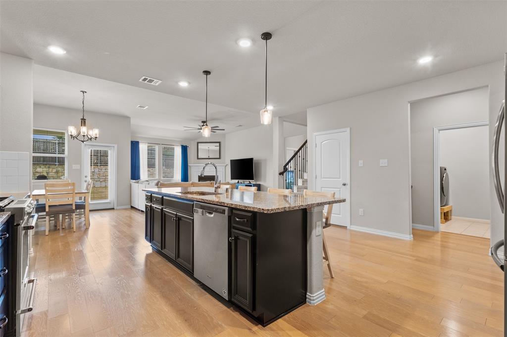 2304 Ravensway Road Crandall, TX 75114 - Photo 22 of 22 a large kitchen with stainless steel appliances a stove a sink a oven a dining table and chairs with wooden floor