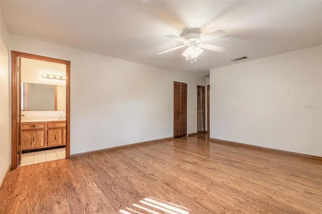 a view of an empty room with window and wooden floor