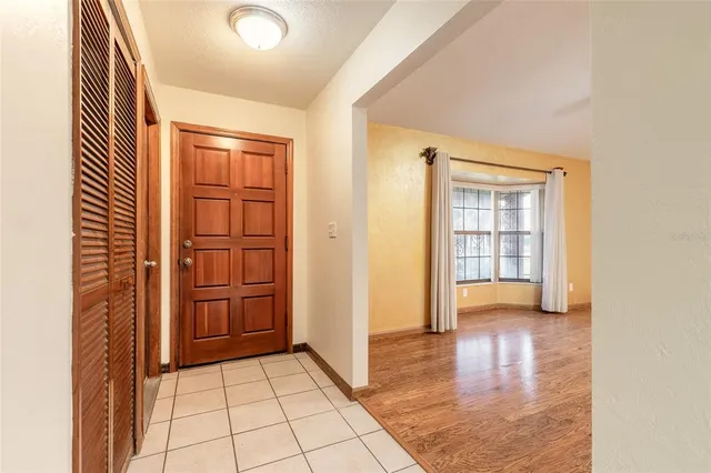 an empty room with kitchen view and wooden floor