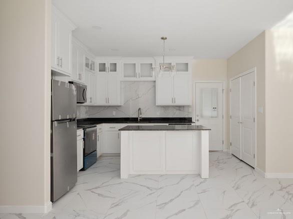 611 Mountain Road, Unit 5B Mission, TX 78573 - Photo 4 of 17 Modern kitchen featuring white cabinetry, a central island with countertop seating, stainless steel appliances, and large format tile flooring