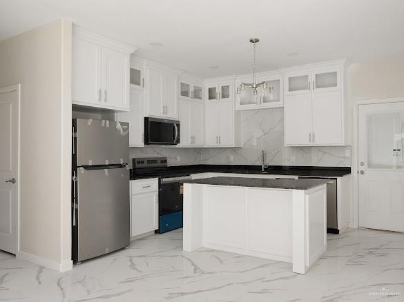 611 Mountain Road, Unit 5B Mission, TX 78573 - Photo 5 of 17 Contemporary kitchen featuring white cabinetry, a central island, stainless steel appliances, dark countertops, and a white marble-look backsplash
