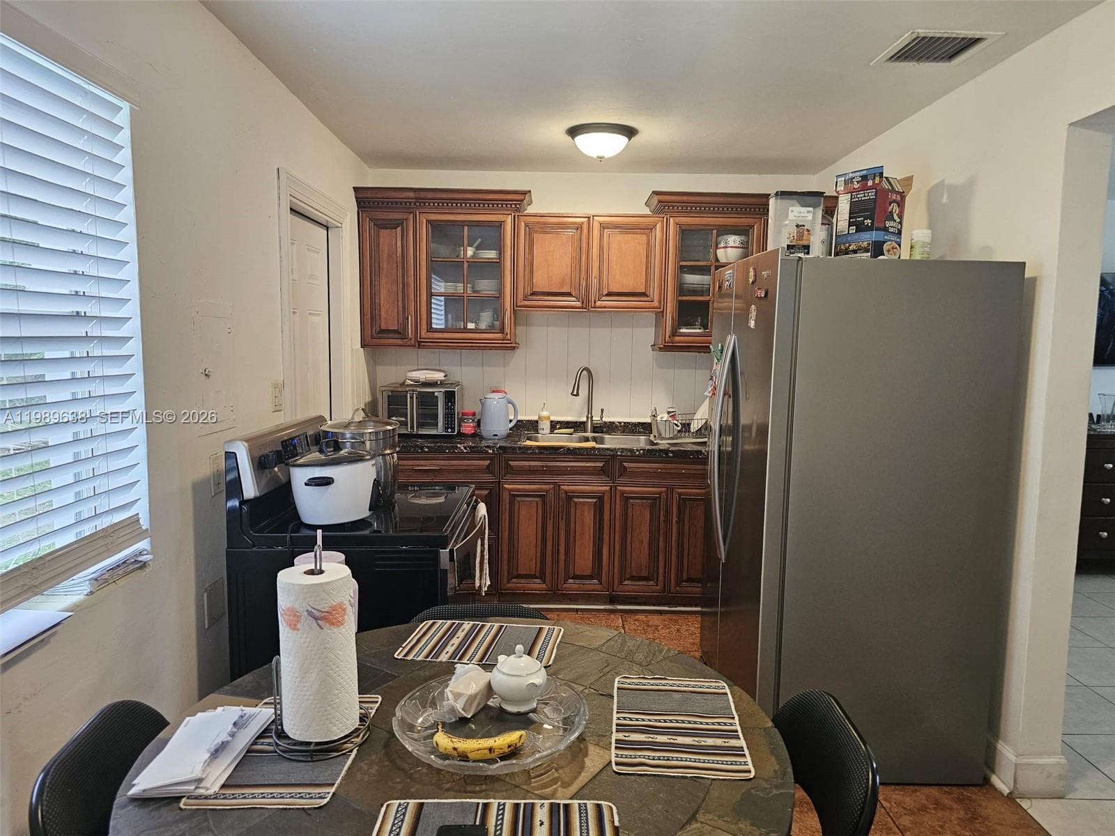 569 Tallulah Road Lake Worth, FL 33462 - Photo 11 of 40 a kitchen with sink refrigerator dining table and chairs