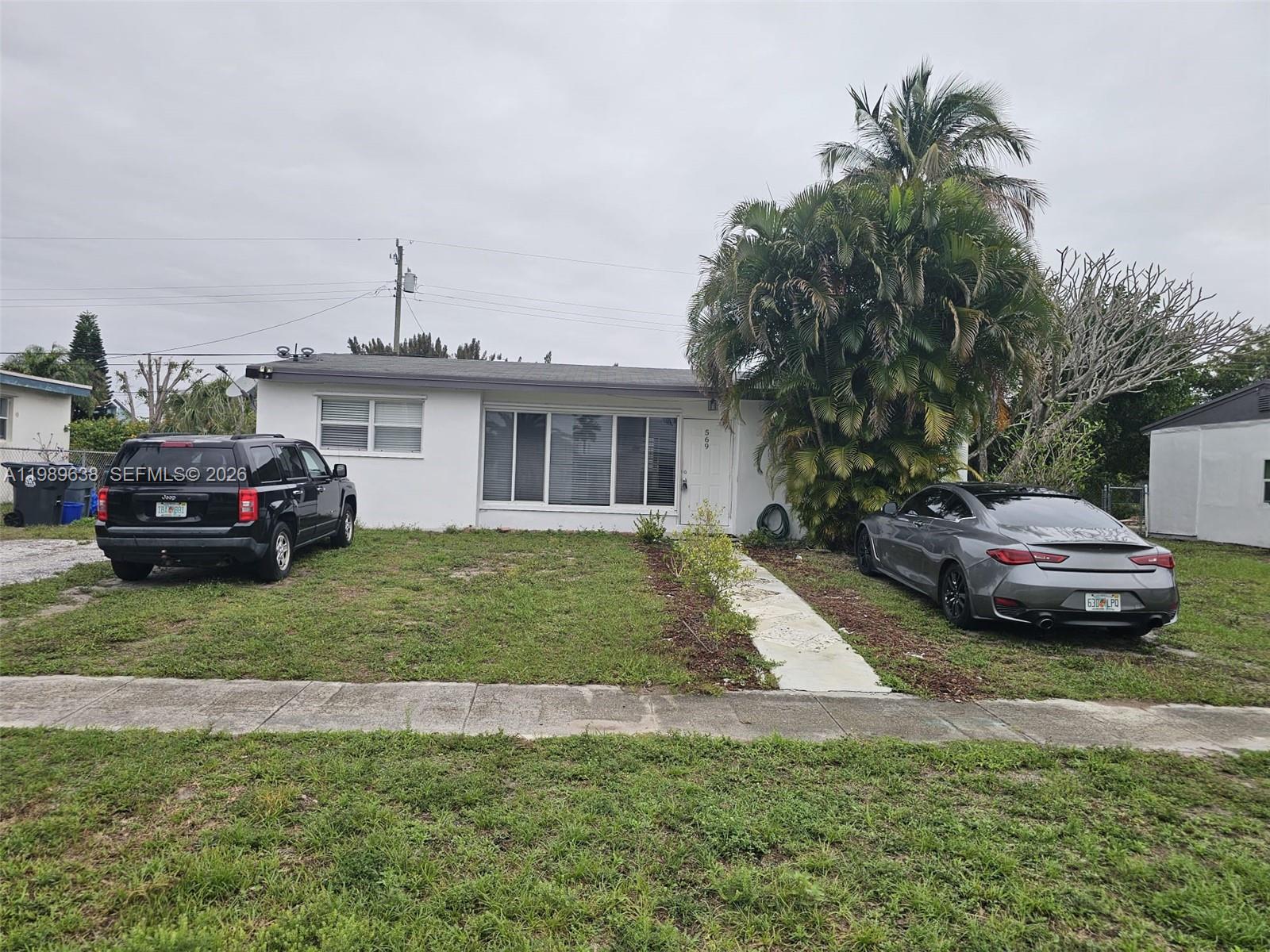 569 Tallulah Road Lake Worth, FL 33462 - Photo 33 of 40 a front view of a house with a garden and parking space