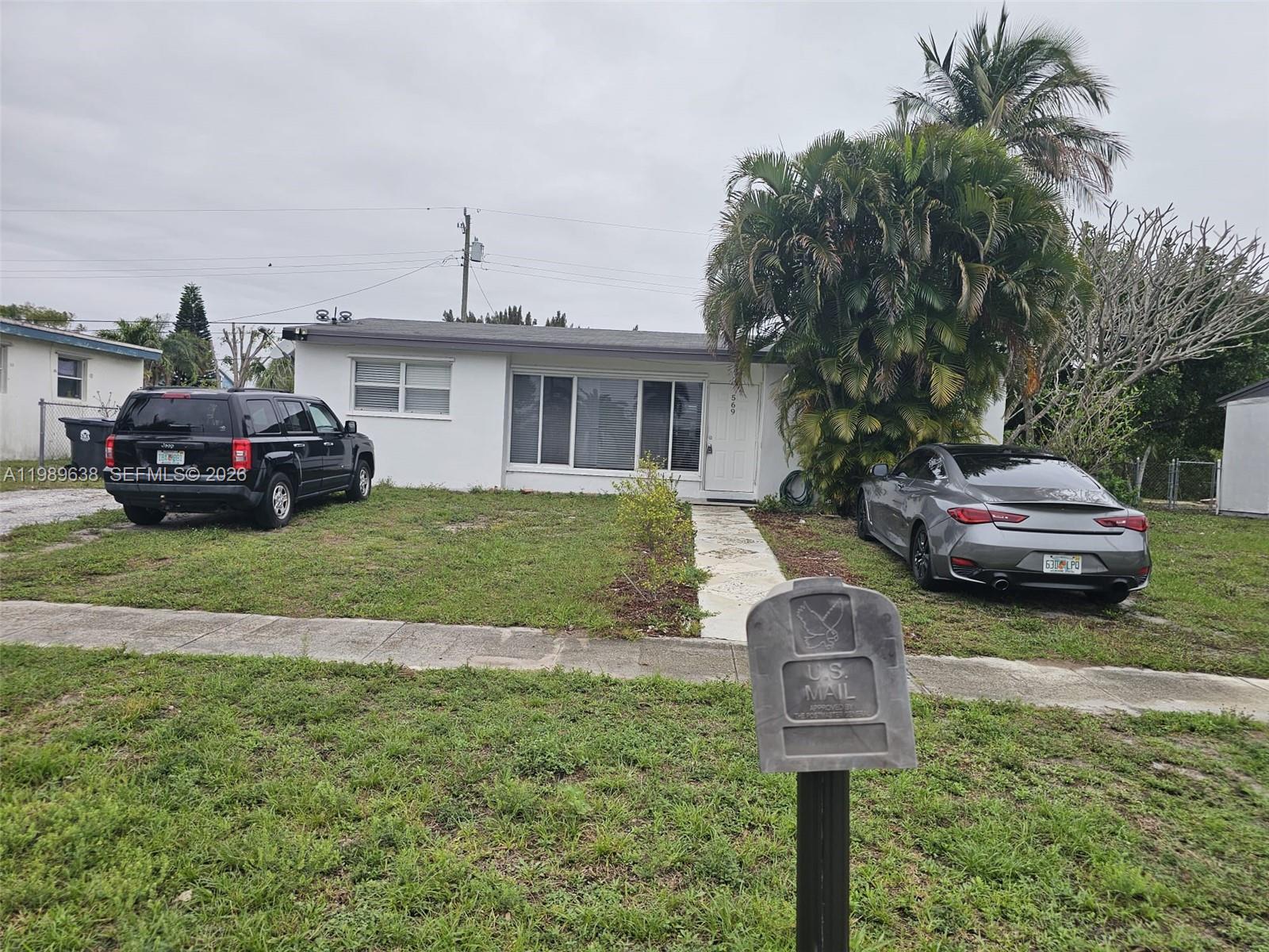 569 Tallulah Road Lake Worth, FL 33462 - Photo 34 of 40 a front view of a house with a garden and parking space