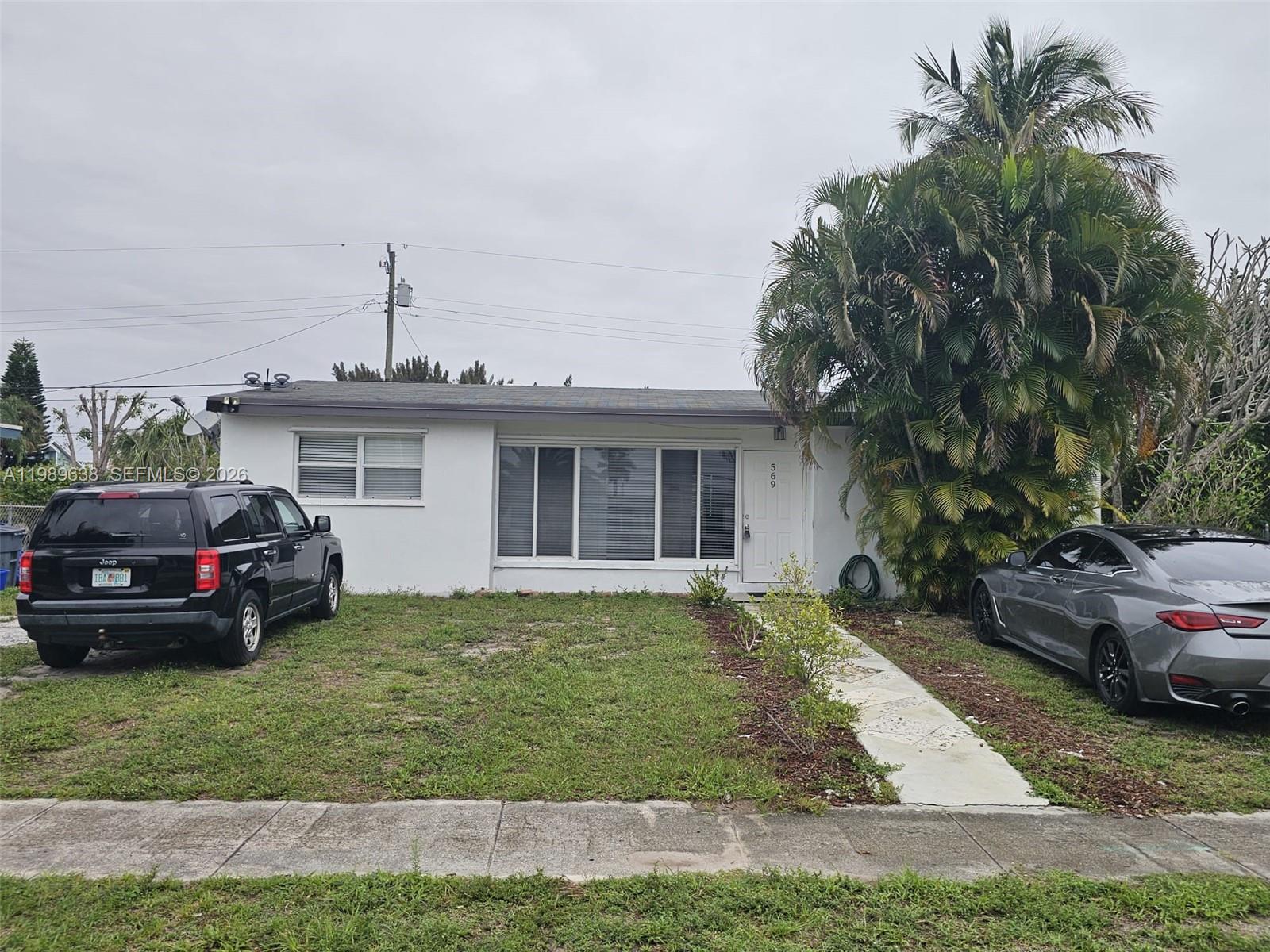 569 Tallulah Road Lake Worth, FL 33462 - Photo 35 of 40 a front view of a house with a garden and trees
